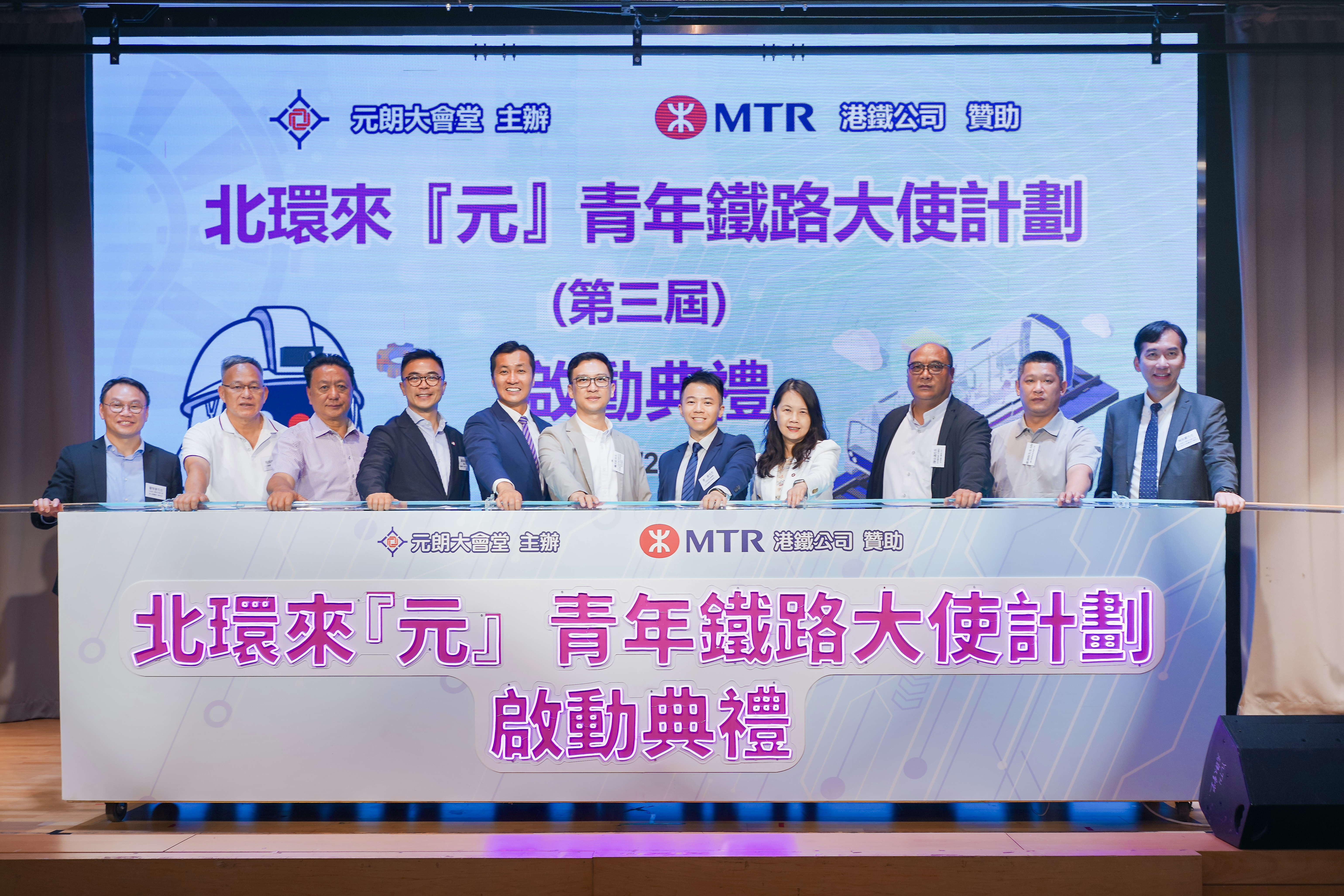 中央人民政府駐香港特別行政區聯絡辦公室新界區事務部副處長龐杰釗先生(左六)、元朗民政事務處民政事務助理專員(二)曾進先生(右五)、港鐵公司企業事務及品牌總監蔡少綿小姐(右四)、港鐵公司項目執行主管 - 北環綫(第一期)羅廸高先生(左四)及一眾主禮嘉賓進行啟動儀式,代表第三屆「北環來『元』 青年鐵路大使計劃」正式展開。